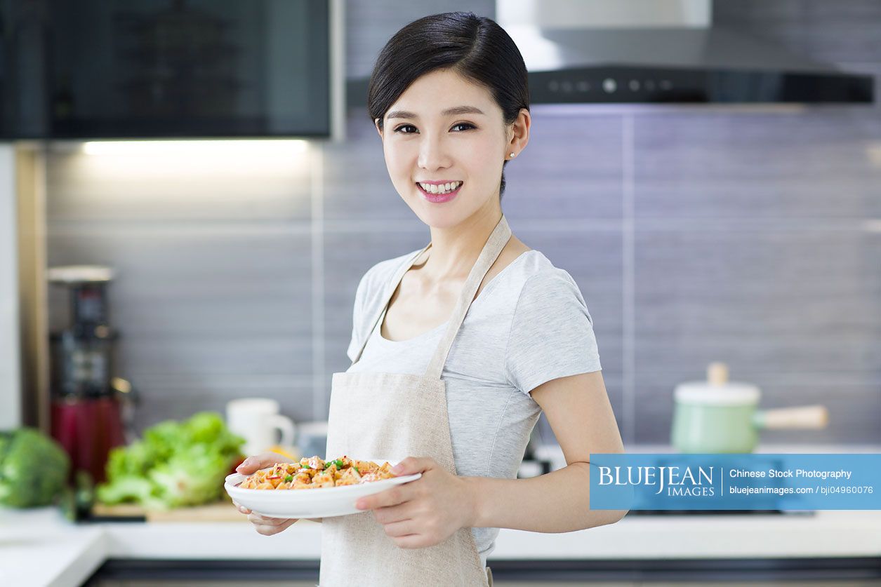Happy young Chinese woman serving food