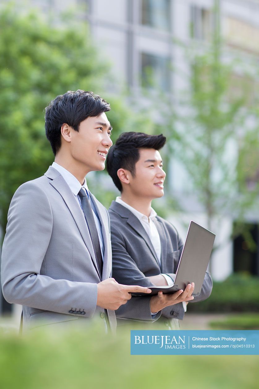 Young Chinese business person working with laptop outdoors