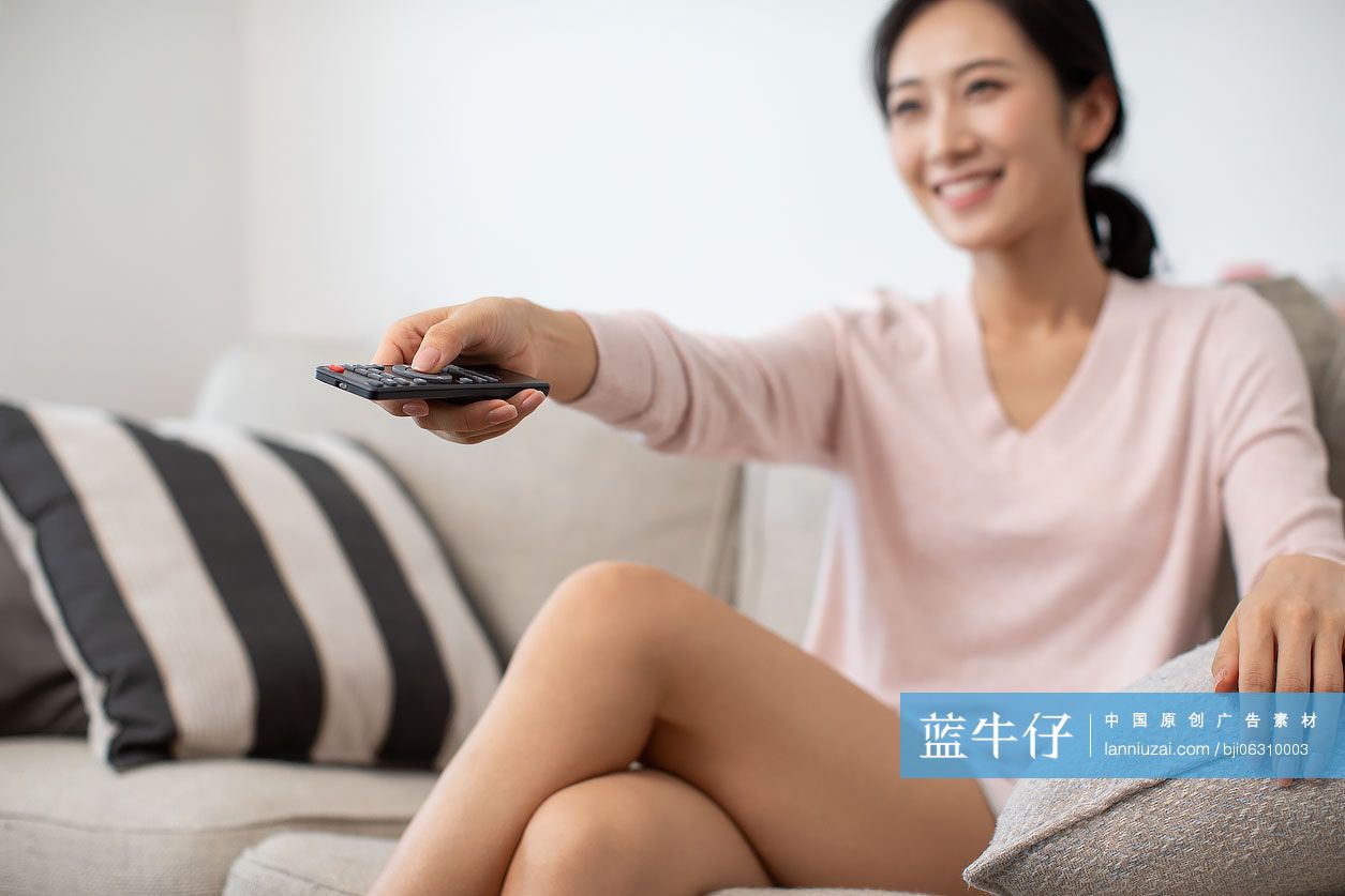 快乐年轻女士在家看电视