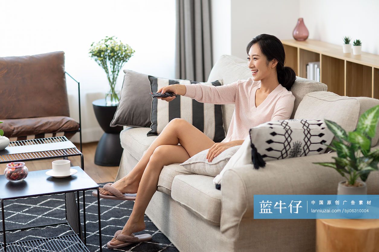 快乐年轻女士在家看电视