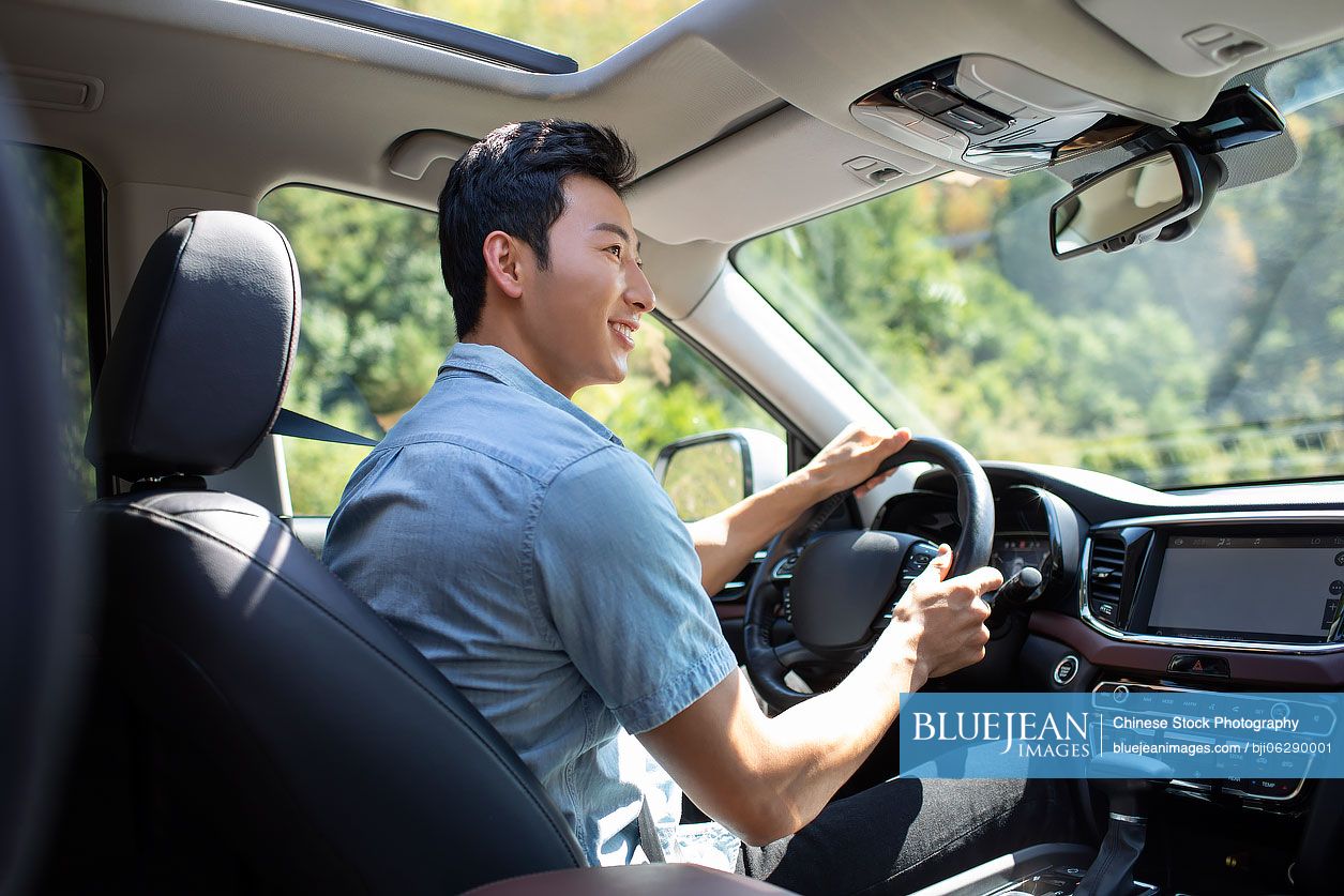 Happy young Chinese man enjoying road trip