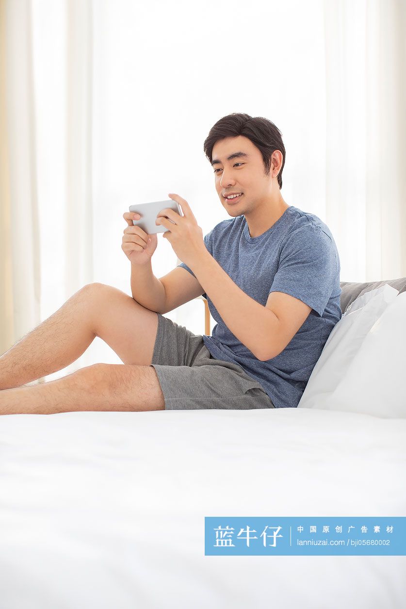 快乐年轻男士在家玩手机游戏