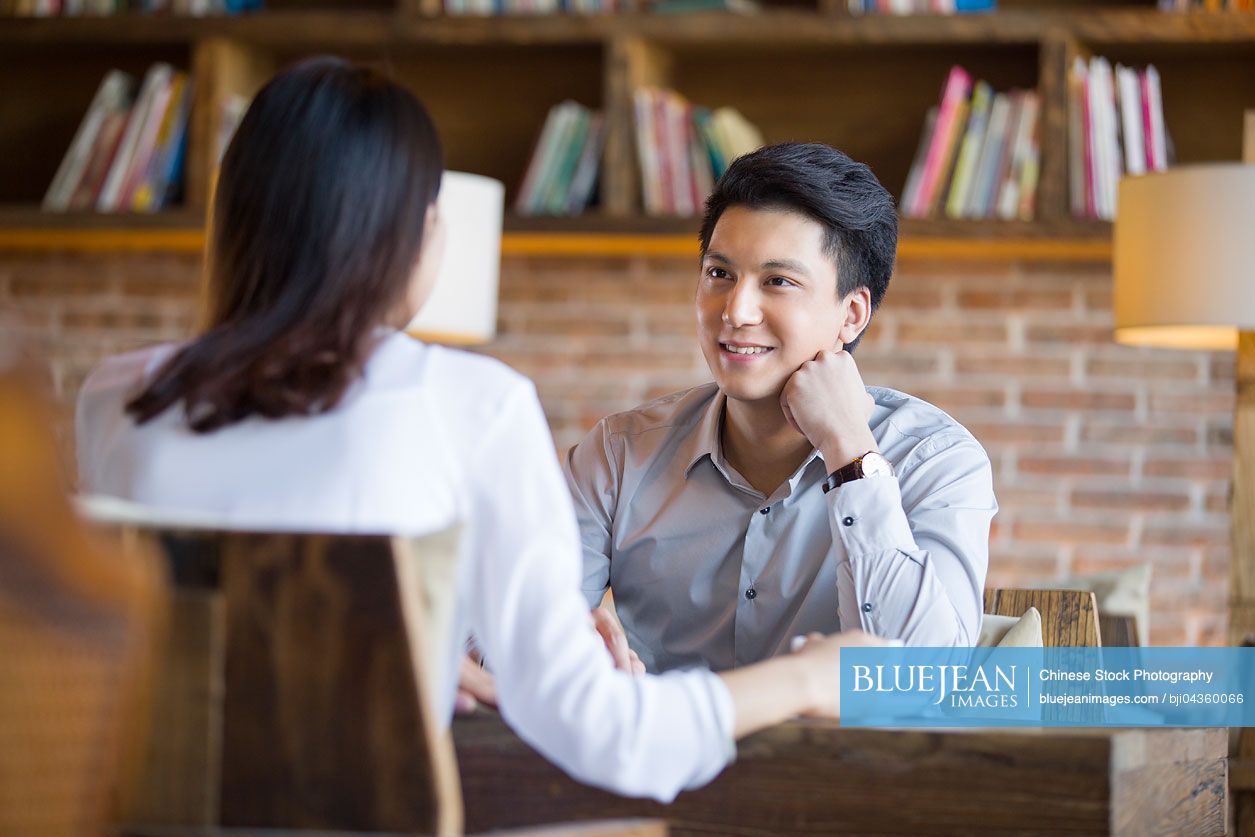 Young Chinese woman and man talking in cafe