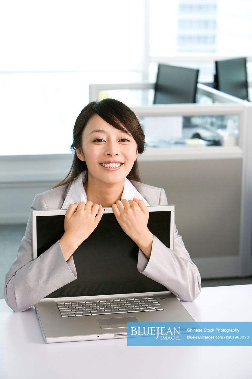 Chinese office worker hugging her computer