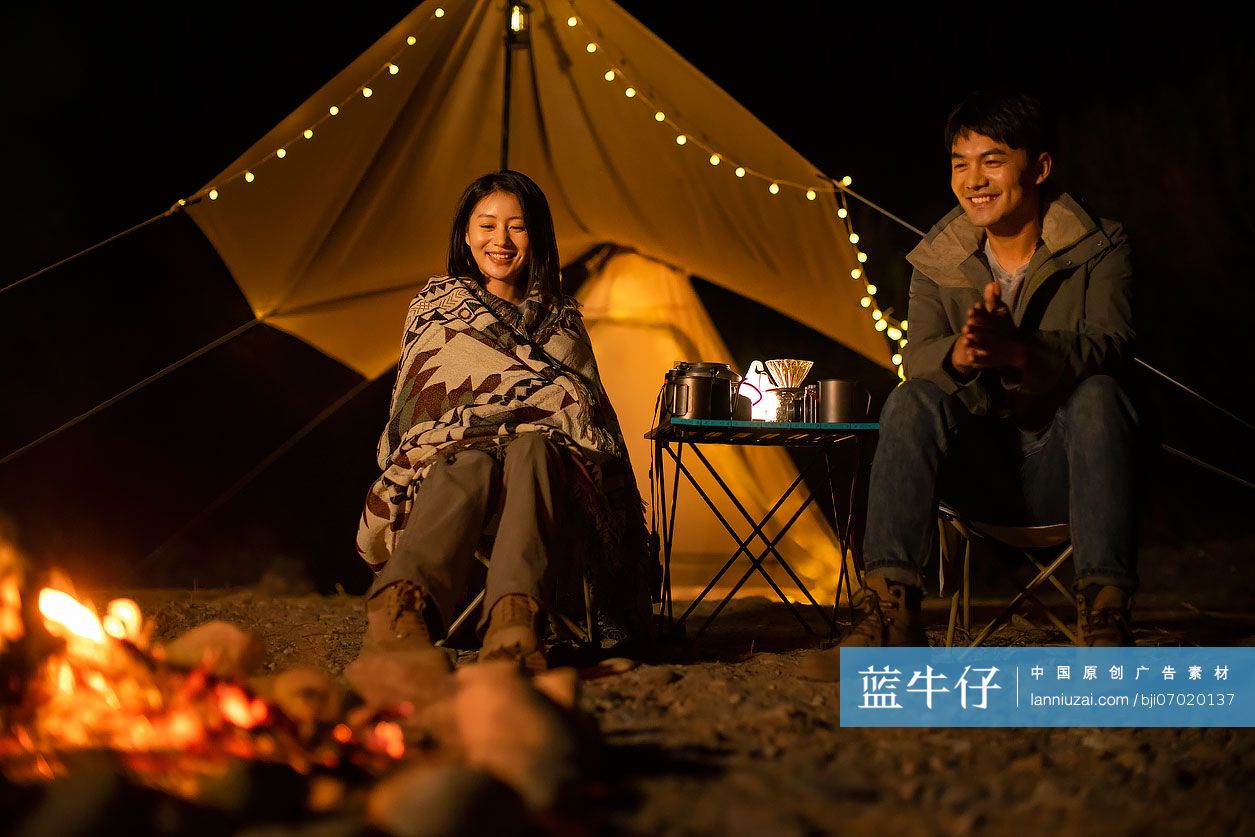 年轻情侣晚上在户外露营烤火