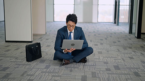 Chinese businessman using laptop on floor in empty office