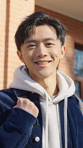 Happy Chinese college boy standing in front of teaching building,HD