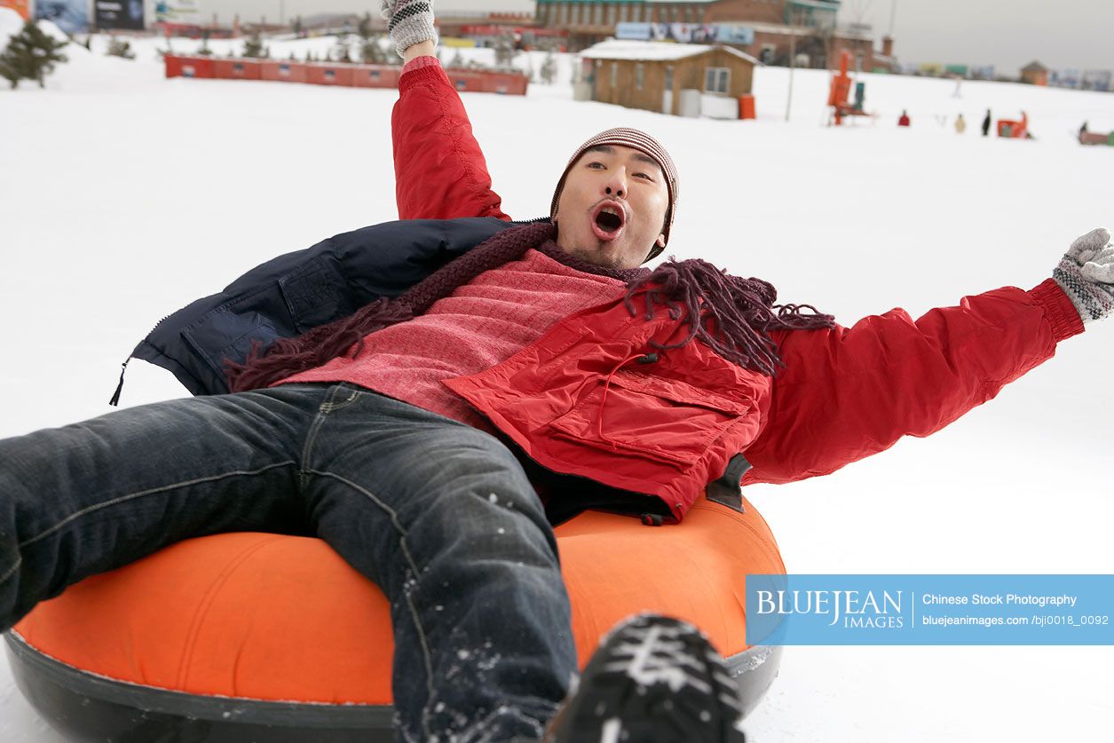 Chinese man riding on inflatable snow tube