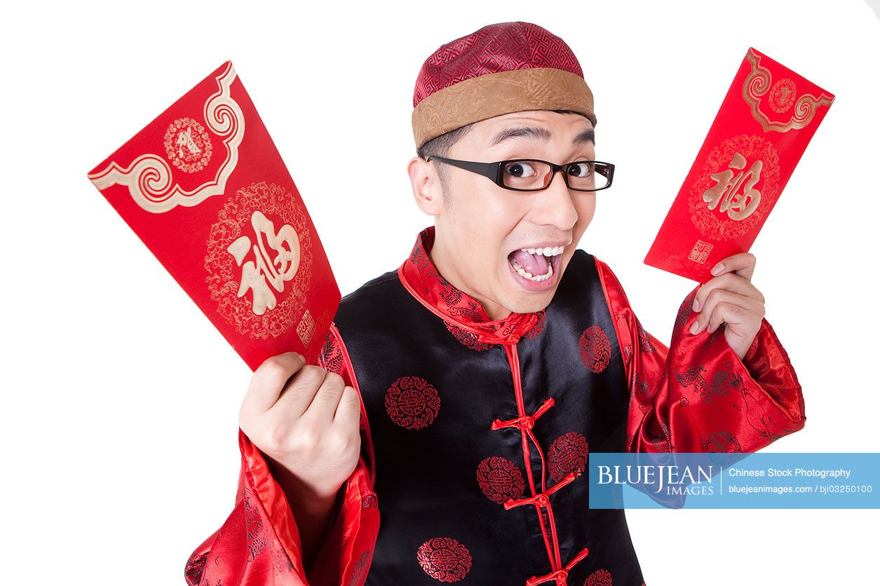 Surprised young Chinese man in traditional clothing showing red pockets