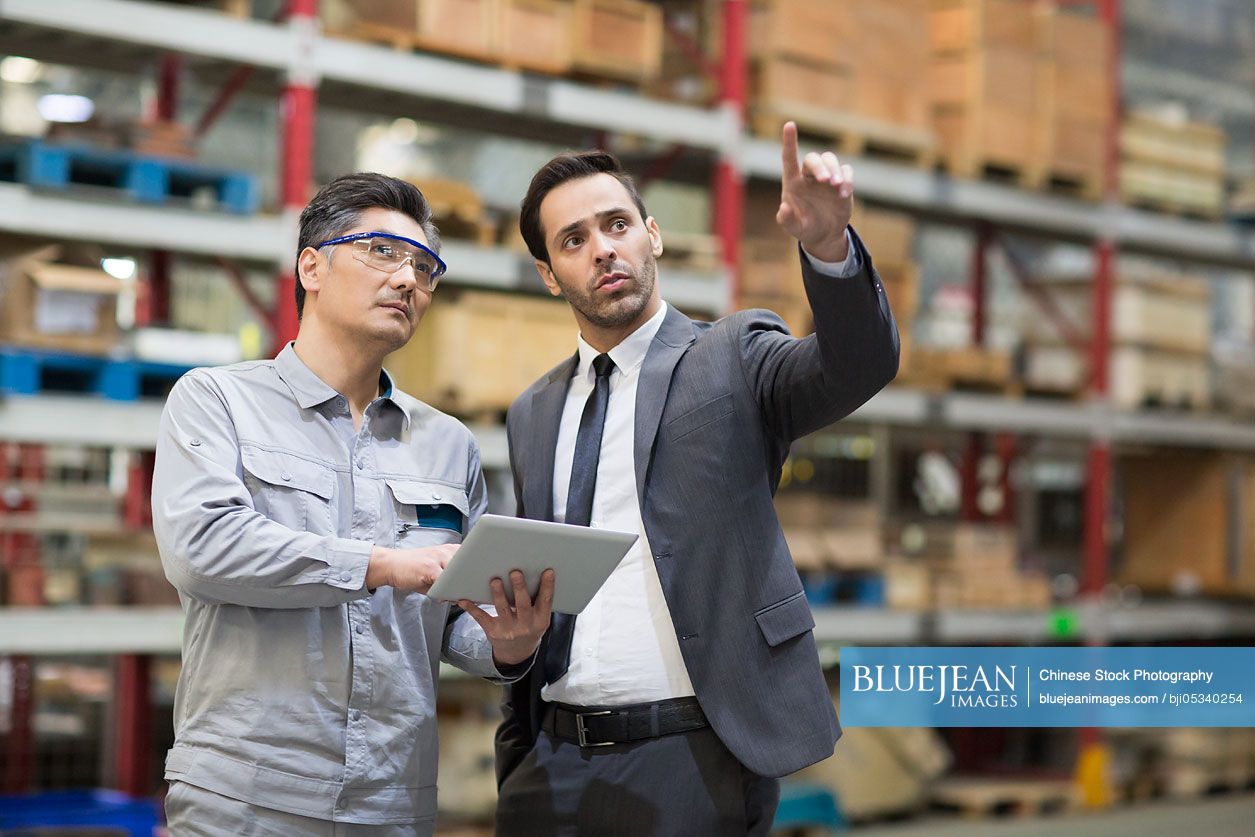 Businessman and engineer talking in the factory