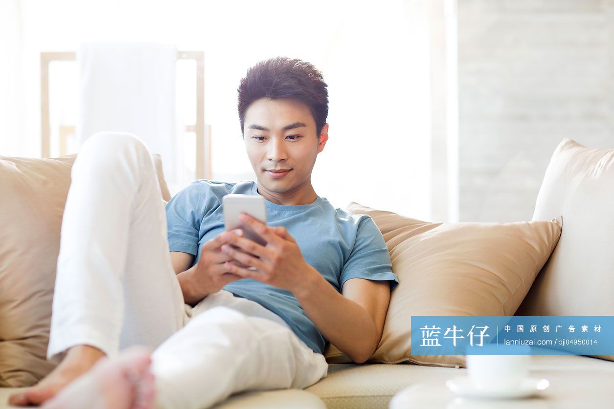 年轻男子在沙发上使用手机