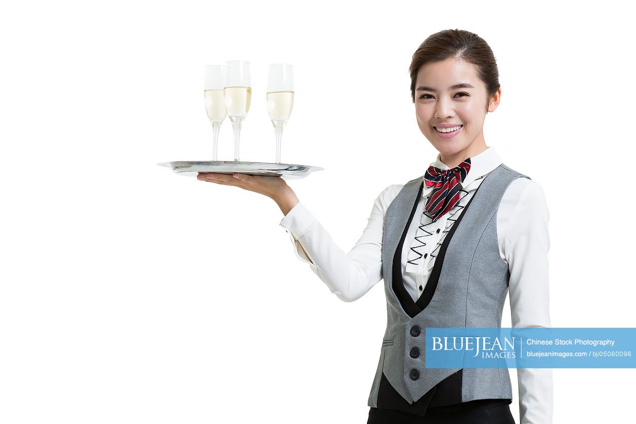 Smiling Chinese waitress in hotel serving champagne