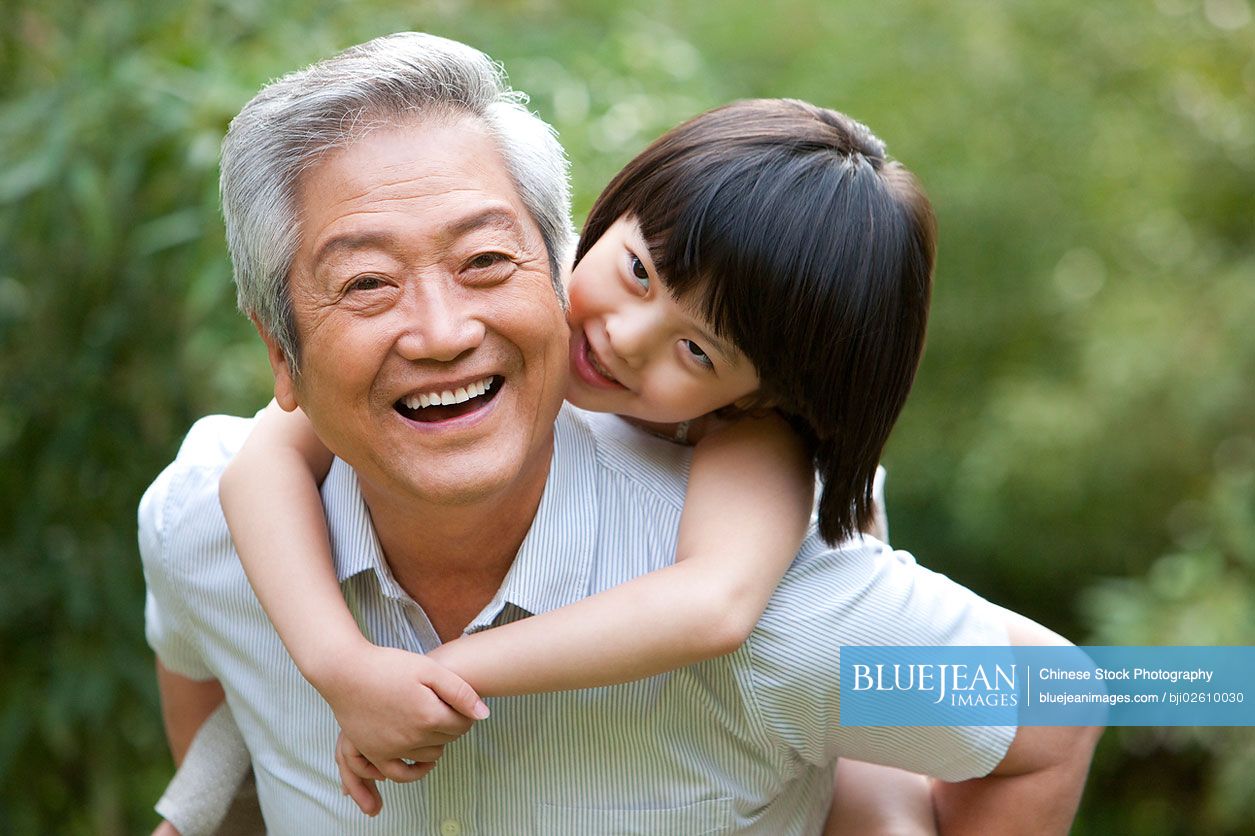 Chinese grandpa and grandaughter having fun in garden