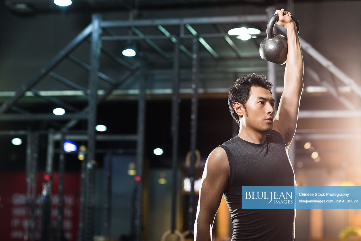 Young Chinese man training with kettlebell in crossfit gym