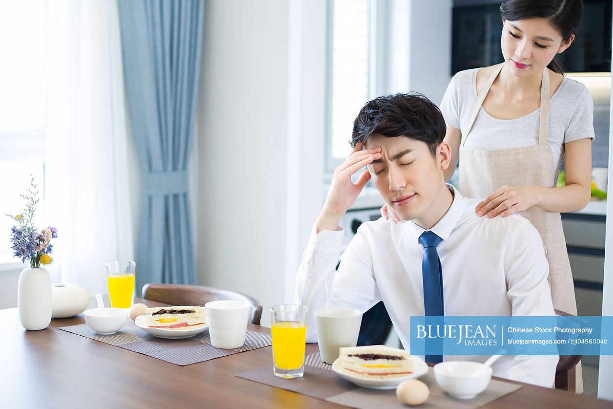 Young Chinese woman massaging her husband's shoulders