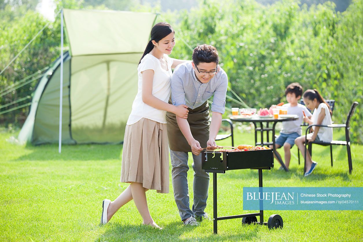 Young Chinese family barbecuing outdoors