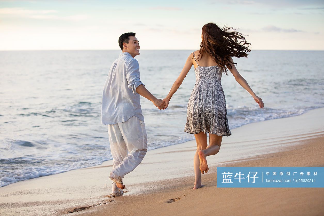 快乐的年轻夫妇在沙滩奔跑