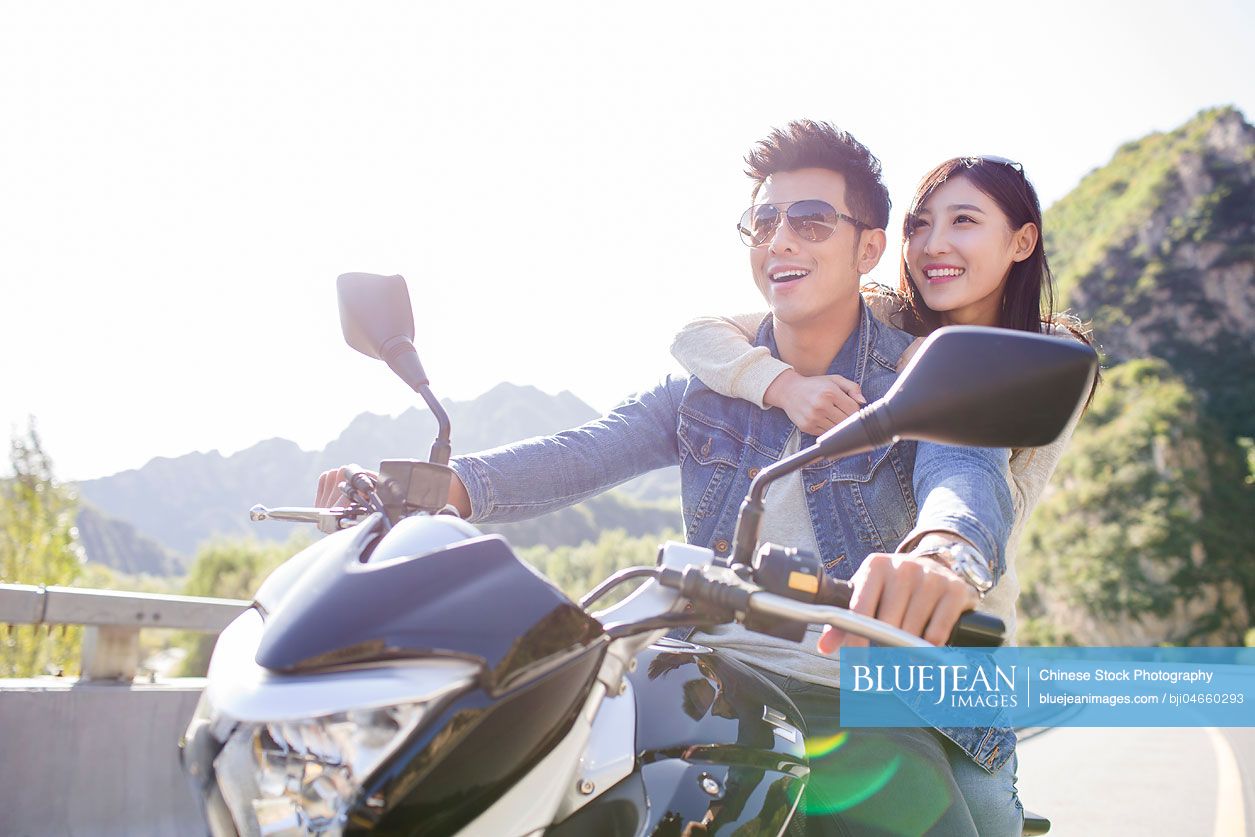 Young Chinese couple riding motorcycle together