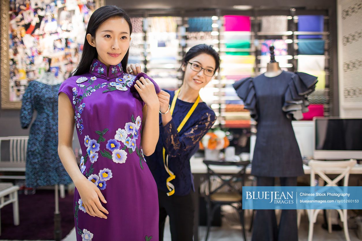 Chinese fashion designer adjusting customer's dress