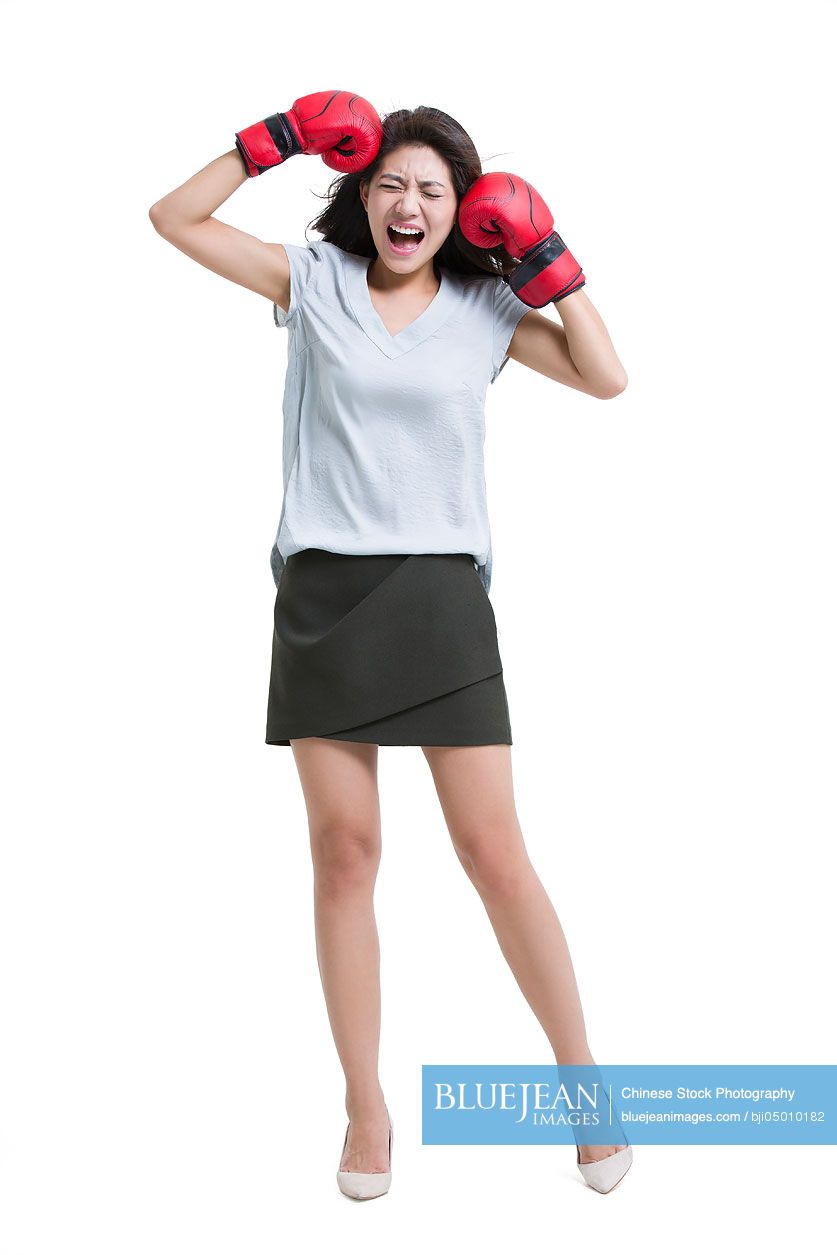 Young Chinese woman shouting with boxing gloves