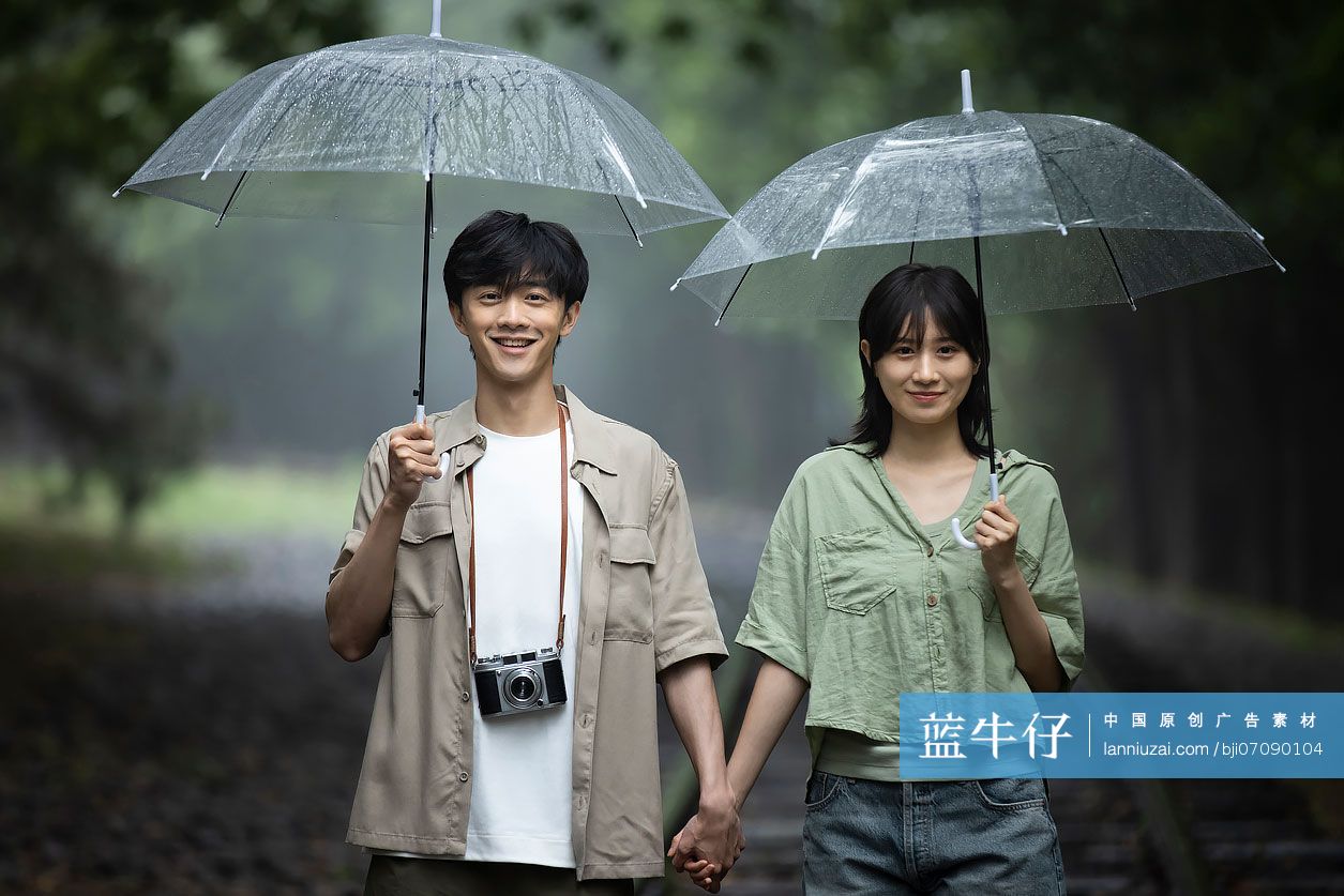 年轻情侣打着伞雨中散步
