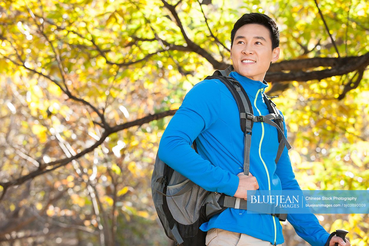 Happy male Chinese backpacker on a hike