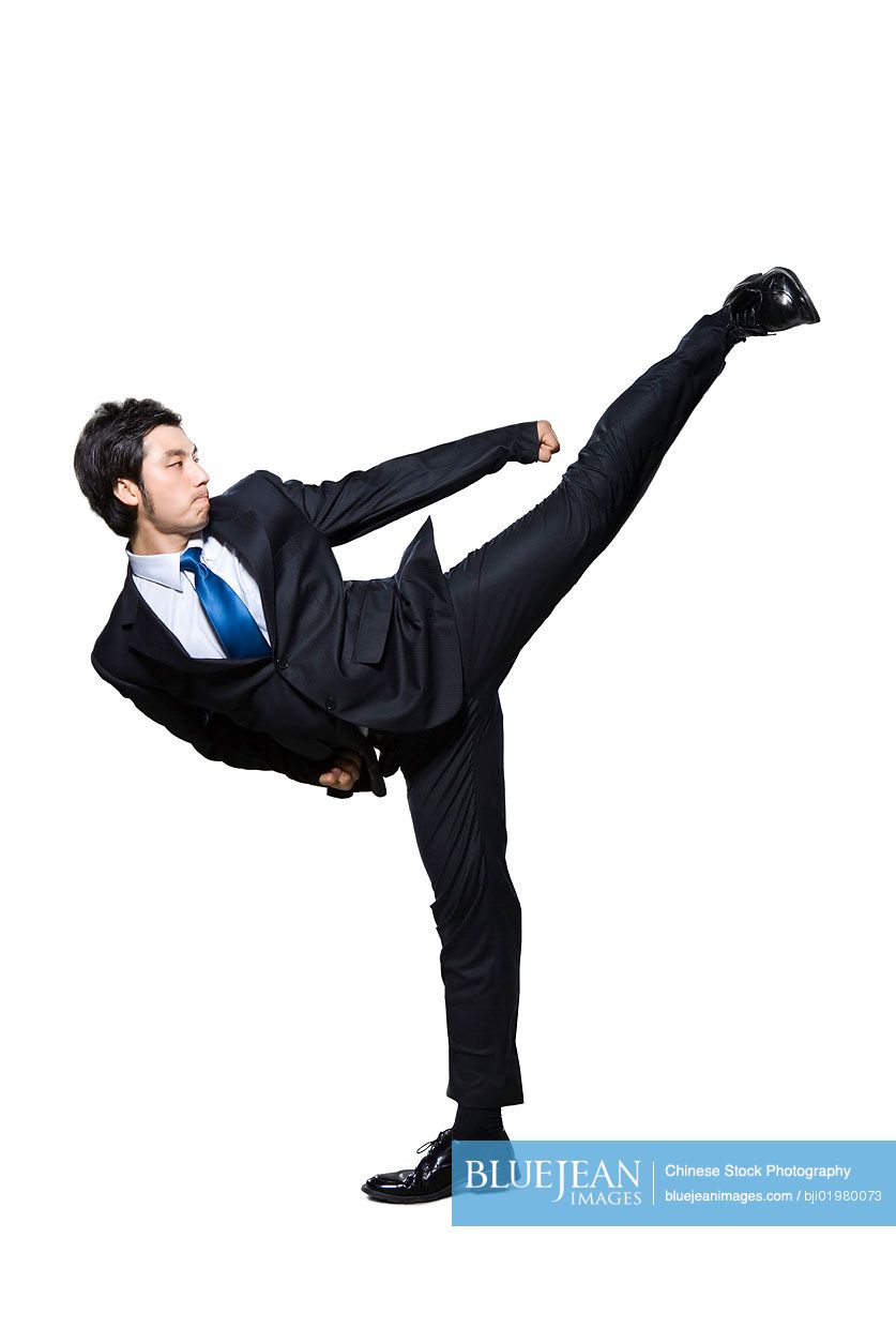 Chinese businessman doing martial arts kick