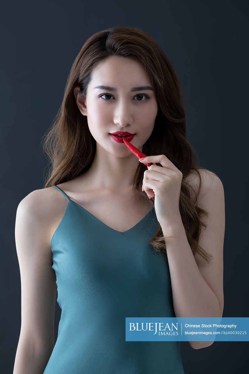 Beautiful young Chinese woman with red chili pepper