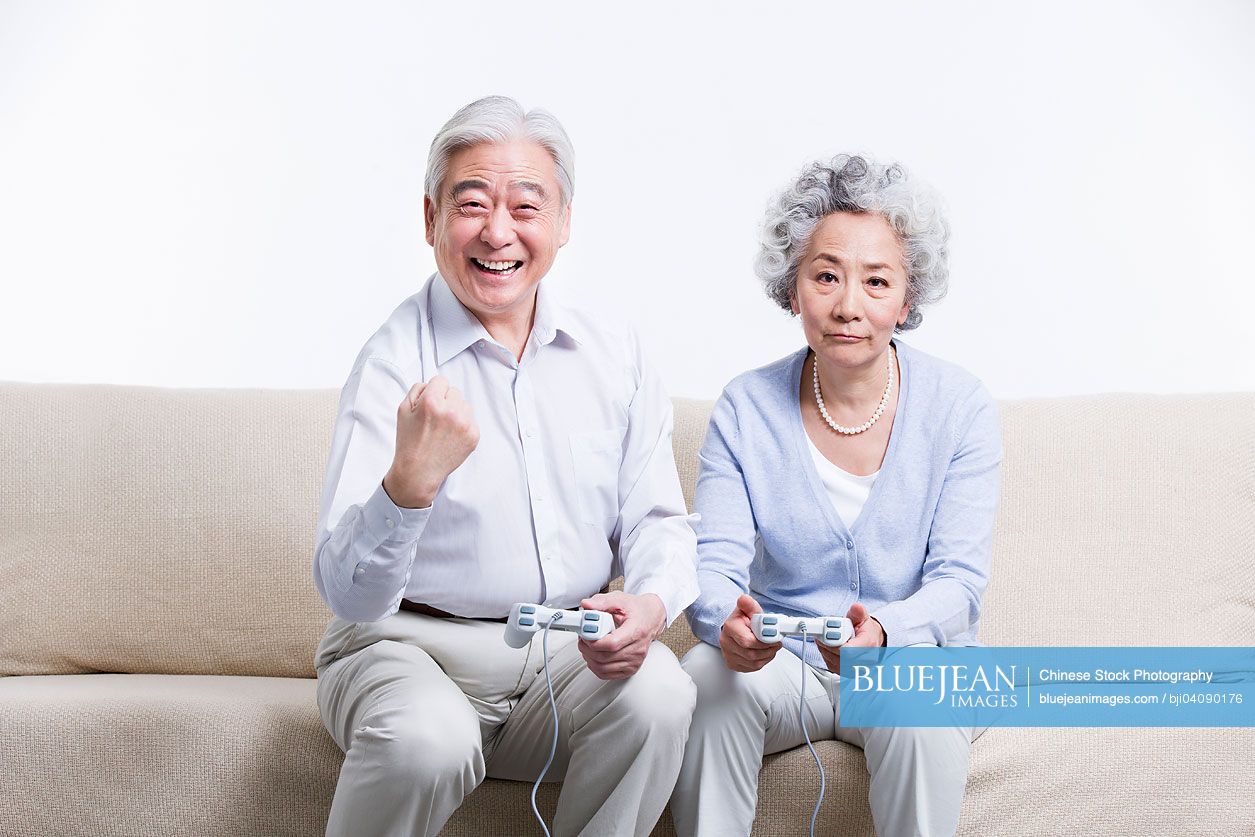 Senior Chinese couple playing video game in living room
