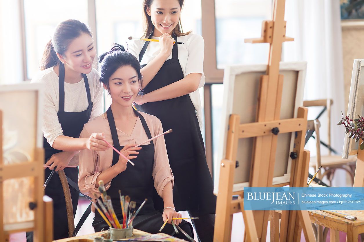 Young Chinese women painting in studio