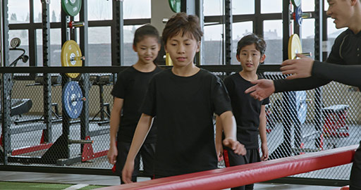 Active Chinese children having exercise class with their coach in gym,4K