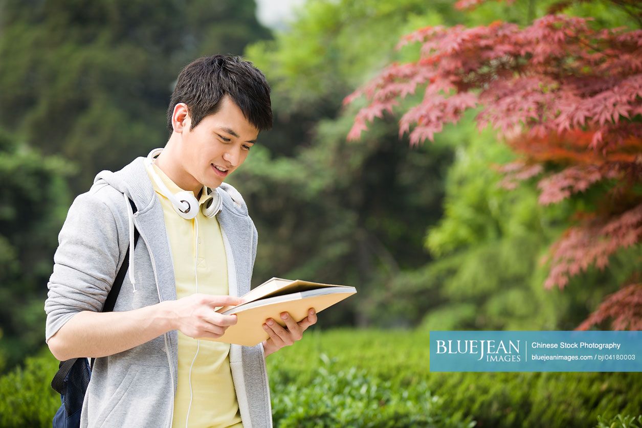 Male Chinese college student reading a book