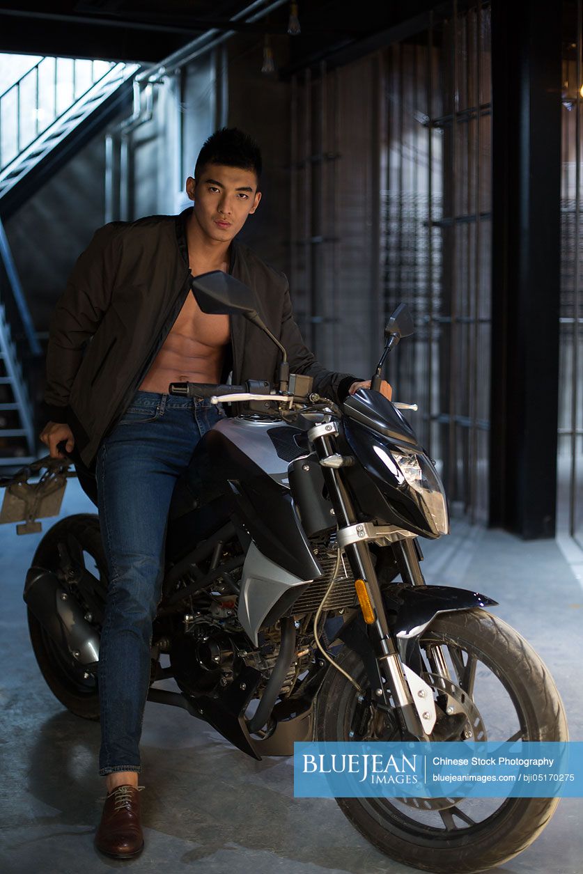 Young Chinese muscular man riding motorcycle