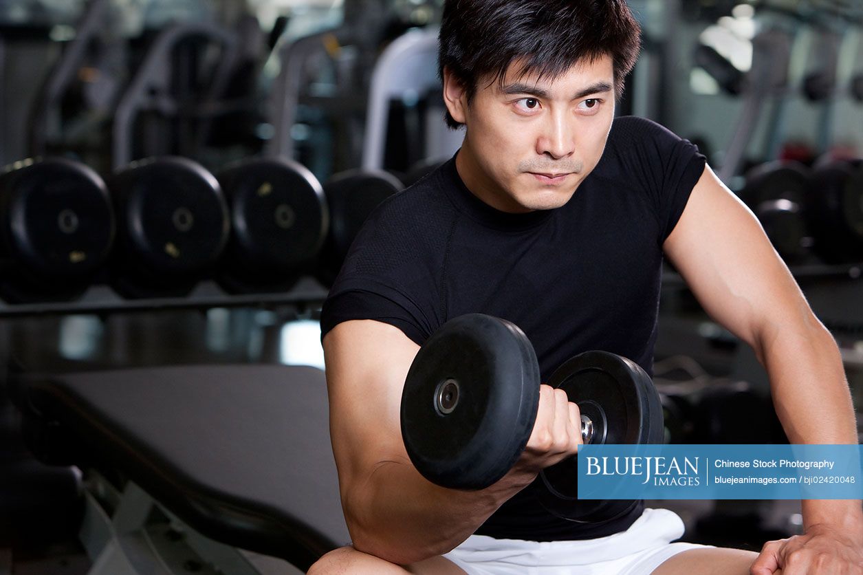 Mid-adult Chinese man lifting weights