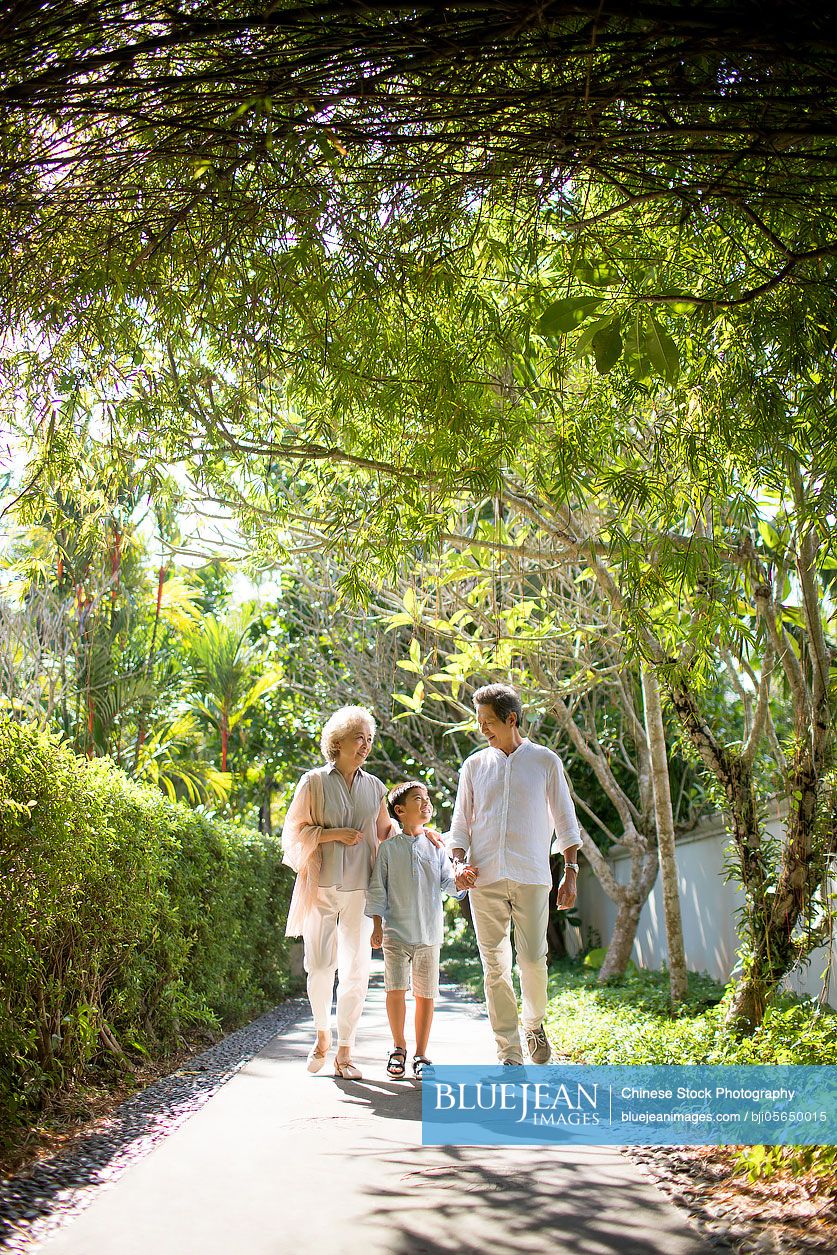 Chinese grandparent and grandson walking in holiday village