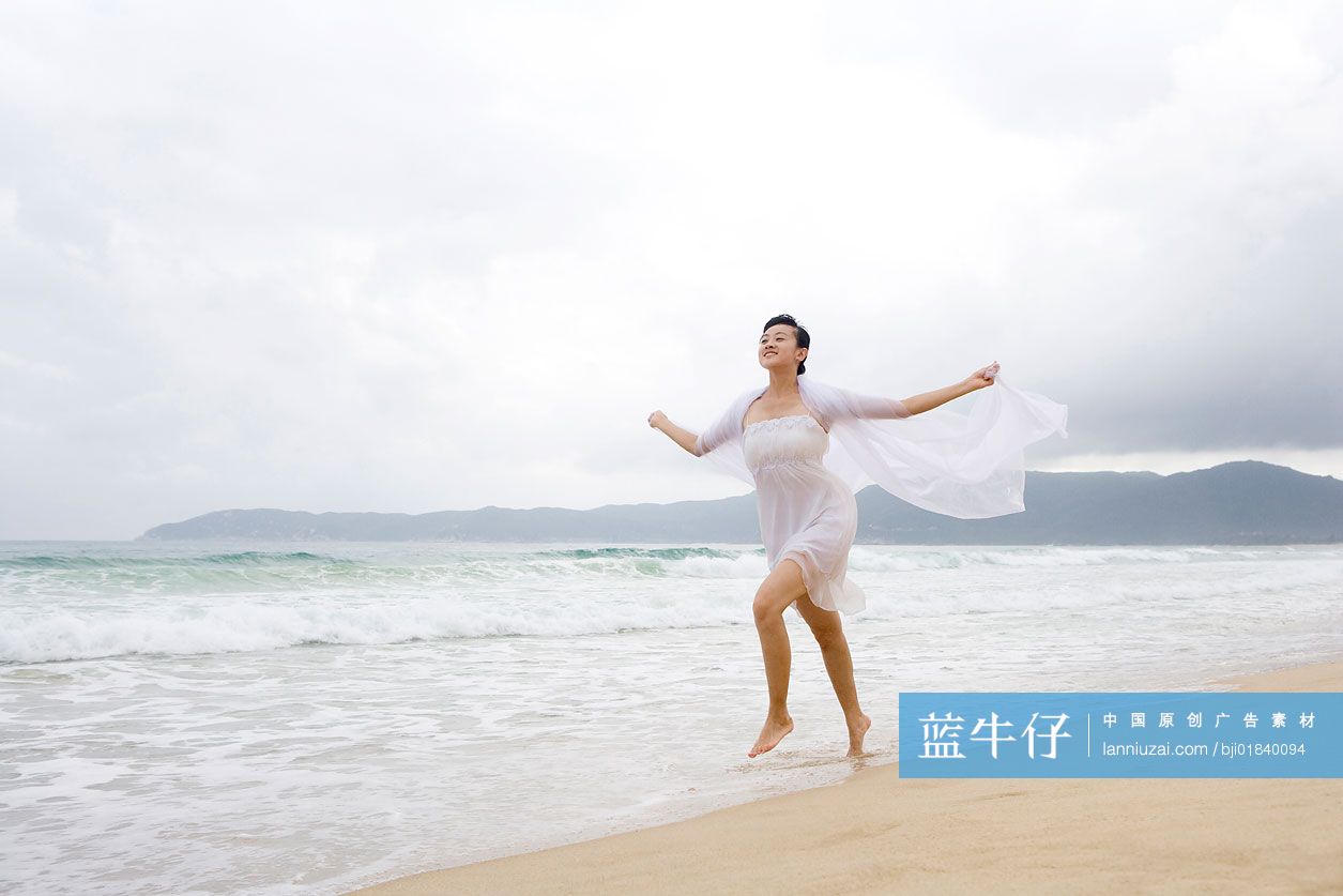 女子海边漫步双手扬纱