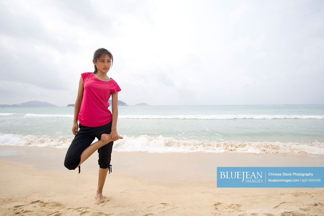 Young Chinese woman stretching by the sea