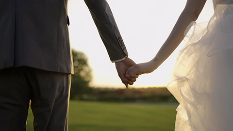 新郎和新娘在草地上牵手走路