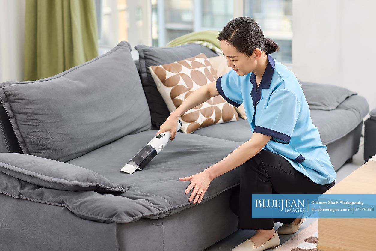 Cleaner vacuuming the sofa
