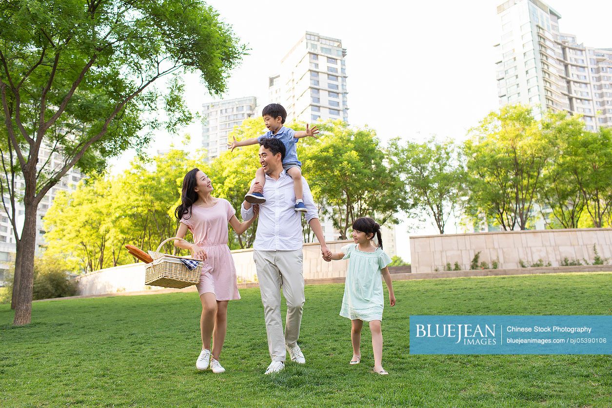 Happy young Chinese family having picnic in park