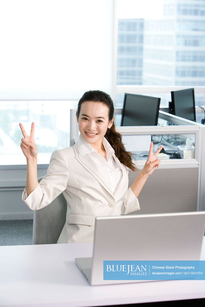Happy Chinese office worker at her desk