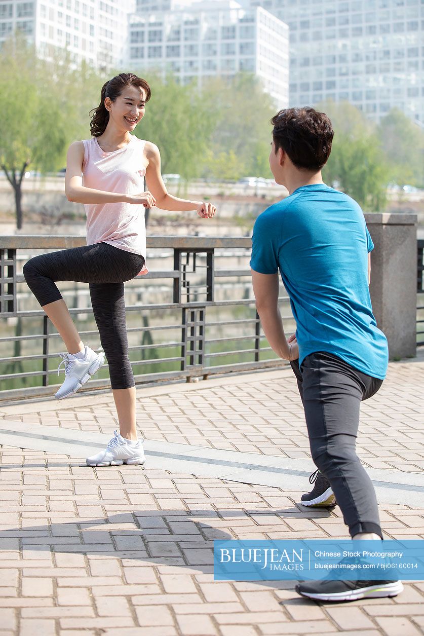 Happy young Chinese couple exercising in park