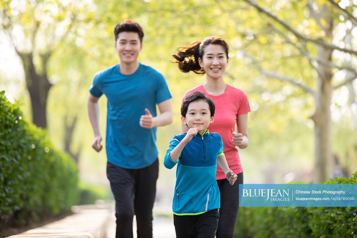 Happy young Chinese family running in park