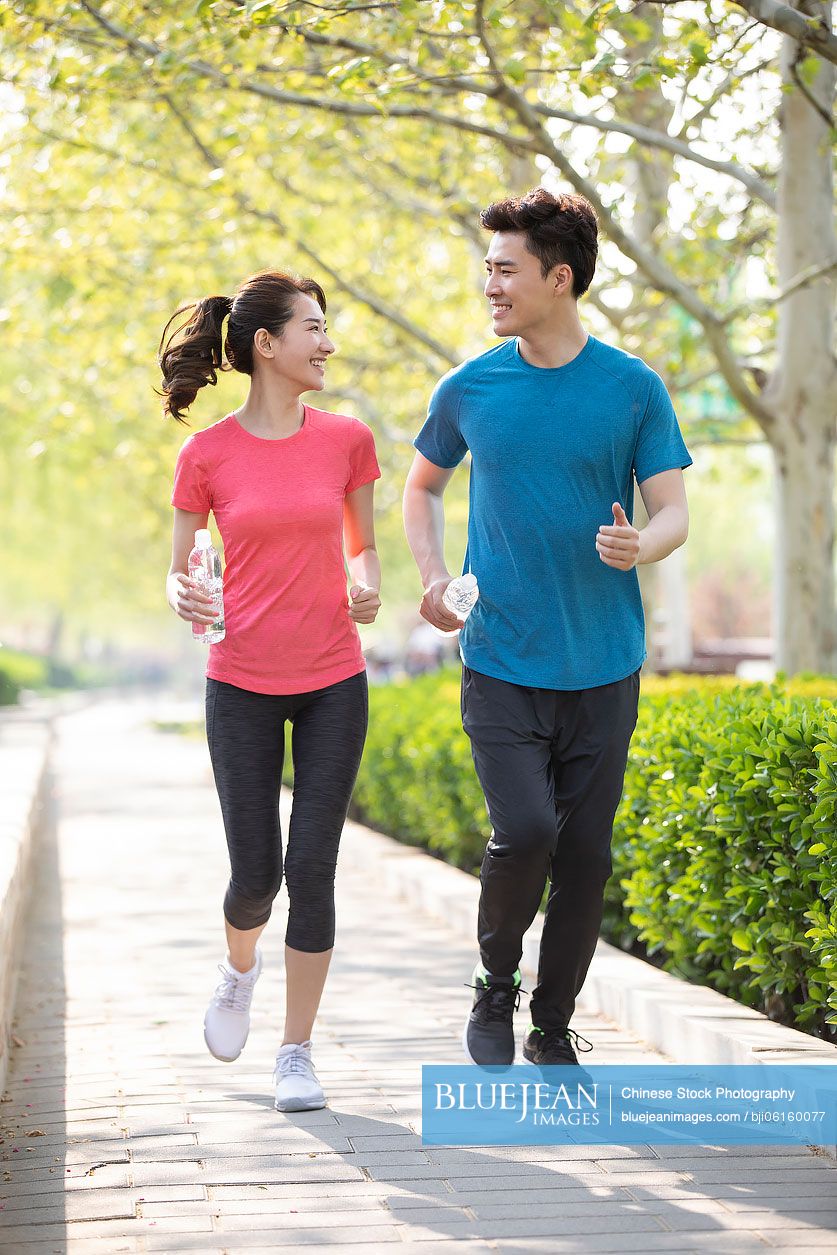 Happy young Chinese couple running in park