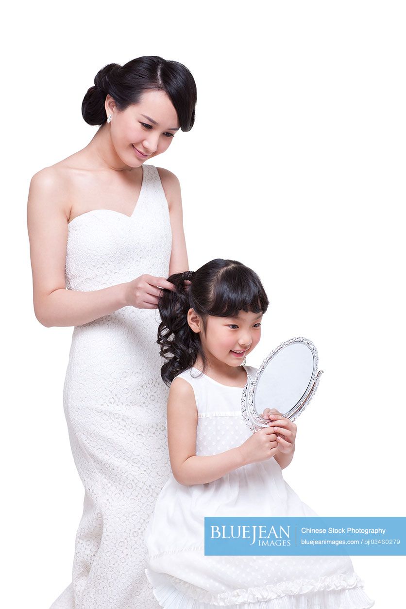 Beautiful Chinese mother tying up little daughter's hair