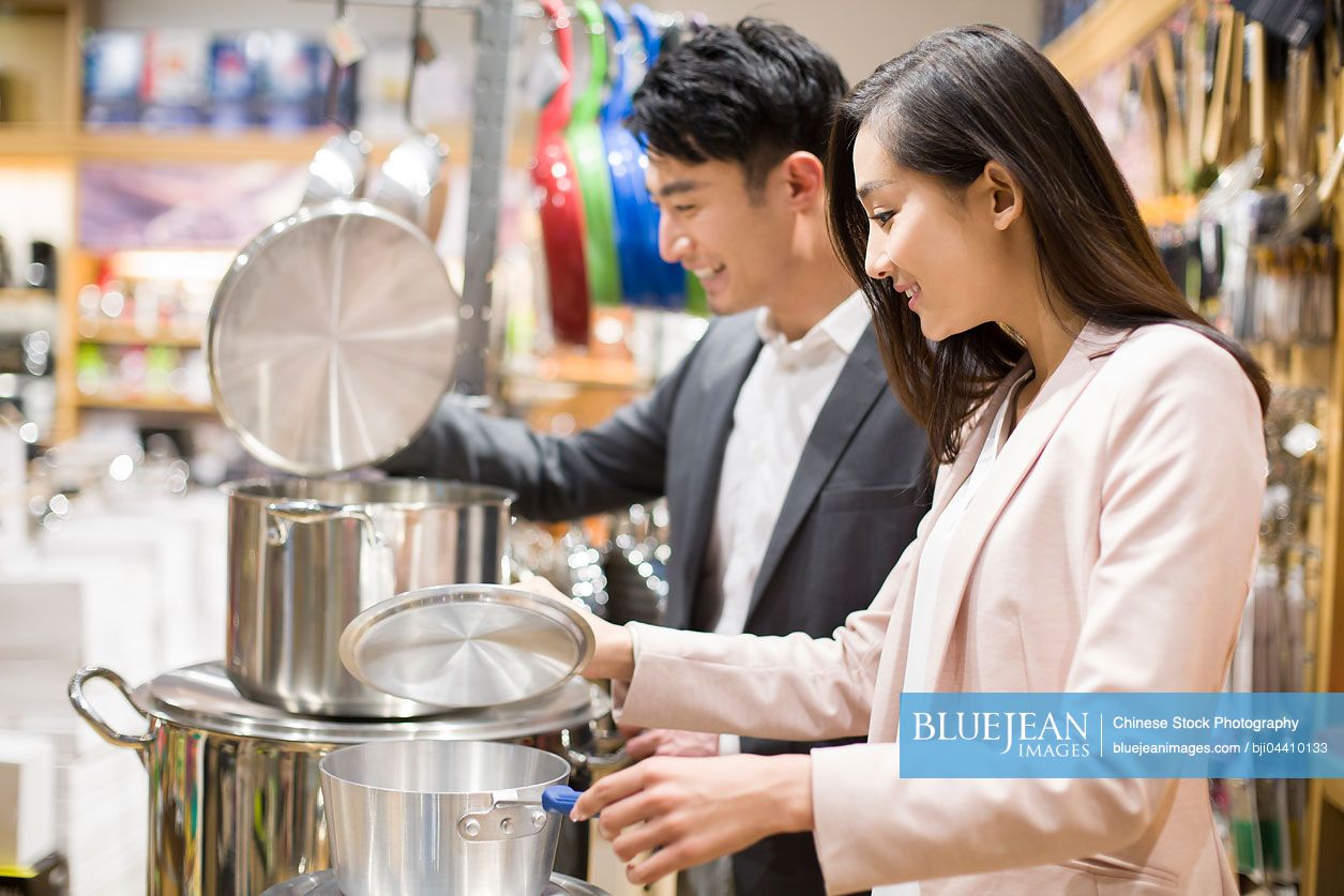 Young Chinese couple buying cooking utensil in supermarket