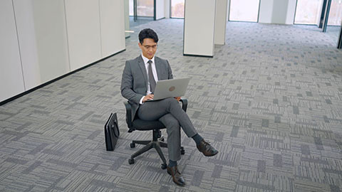 Confident Chinese businessman using laptop in empty office