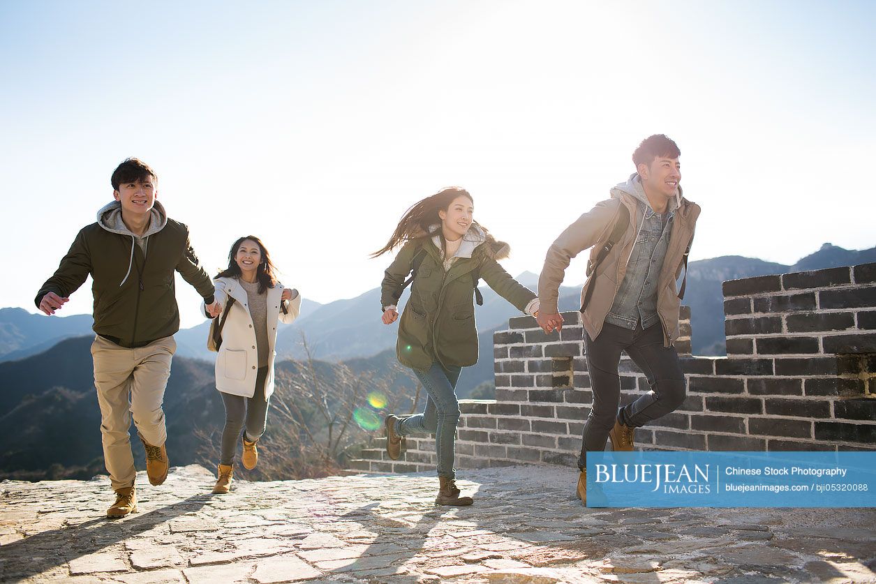 Happy young Chinese friends enjoying winter outing on the Great Wall