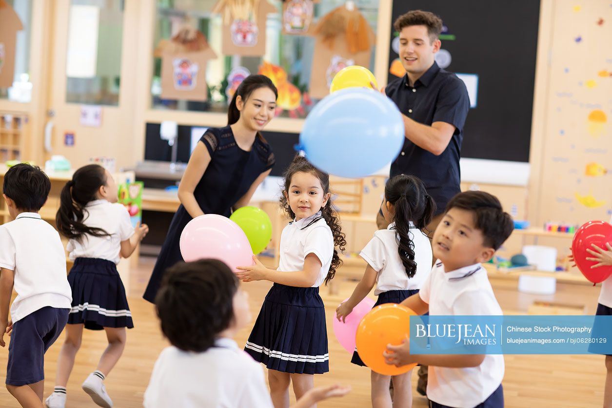 Teachers and children playing in classroom