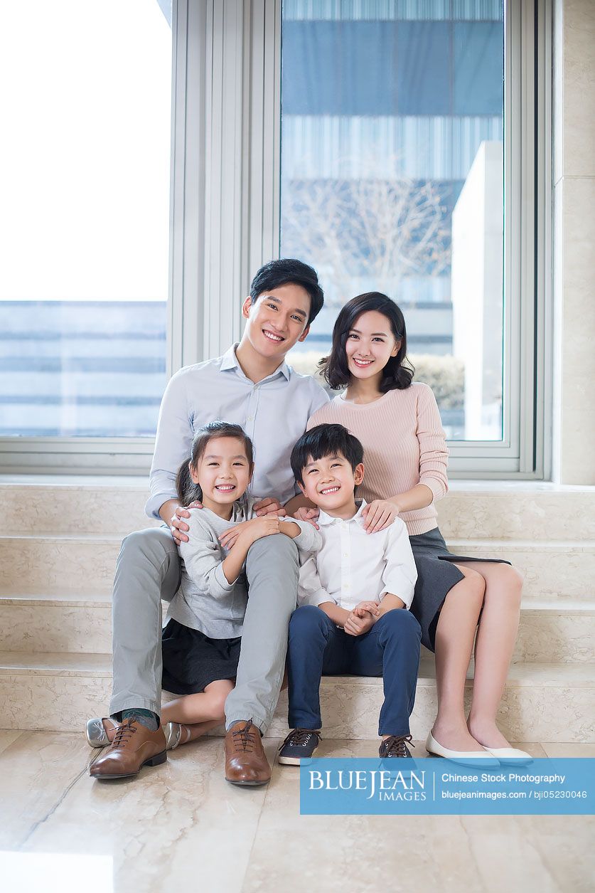 Portrait of cheerful young Chinese family in the living room